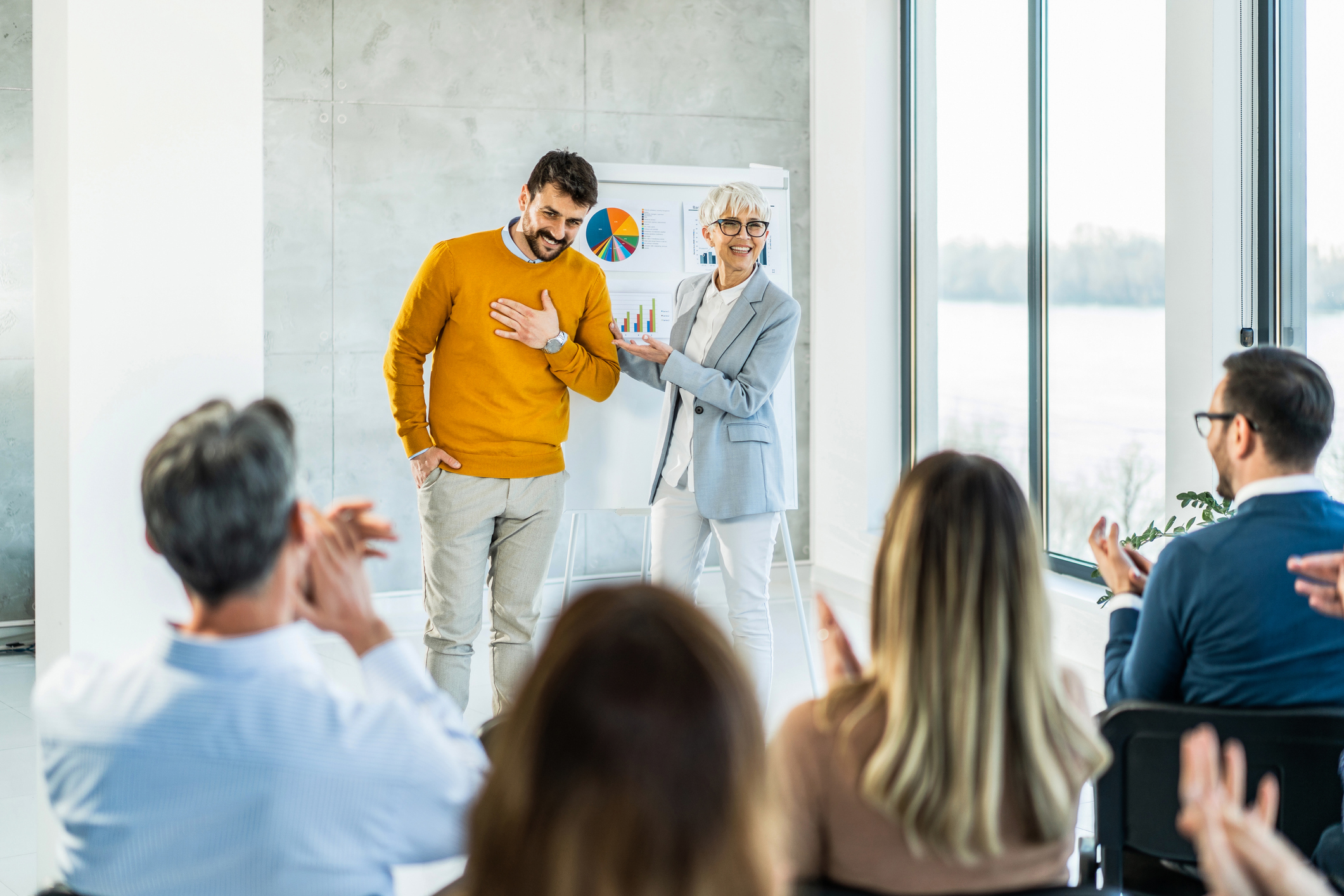 Large group of happy business people applauding and congratulating a young man. Positive work culture.