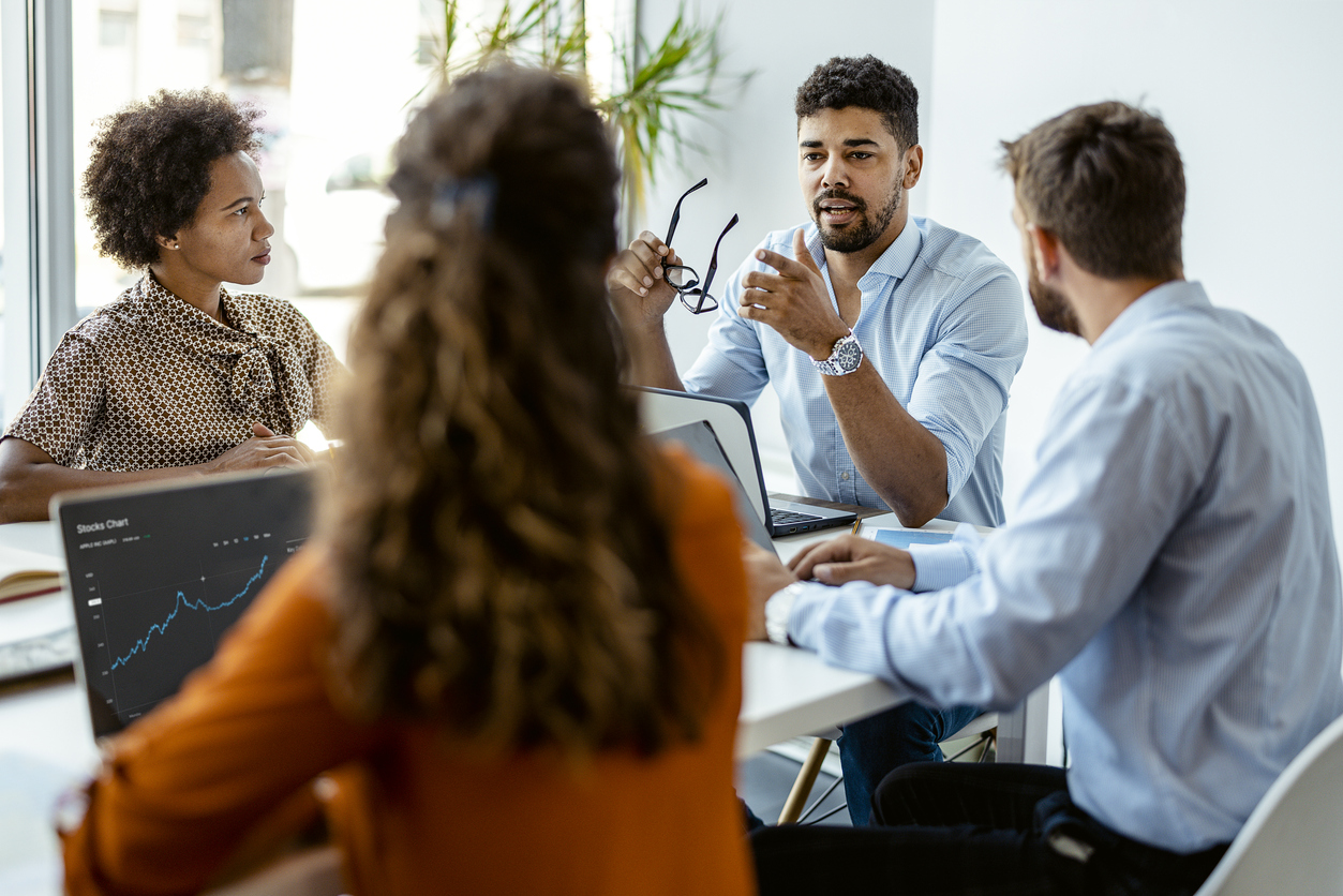 Group of young modern people in smart casual wear discussing business while sitting in the creative office.