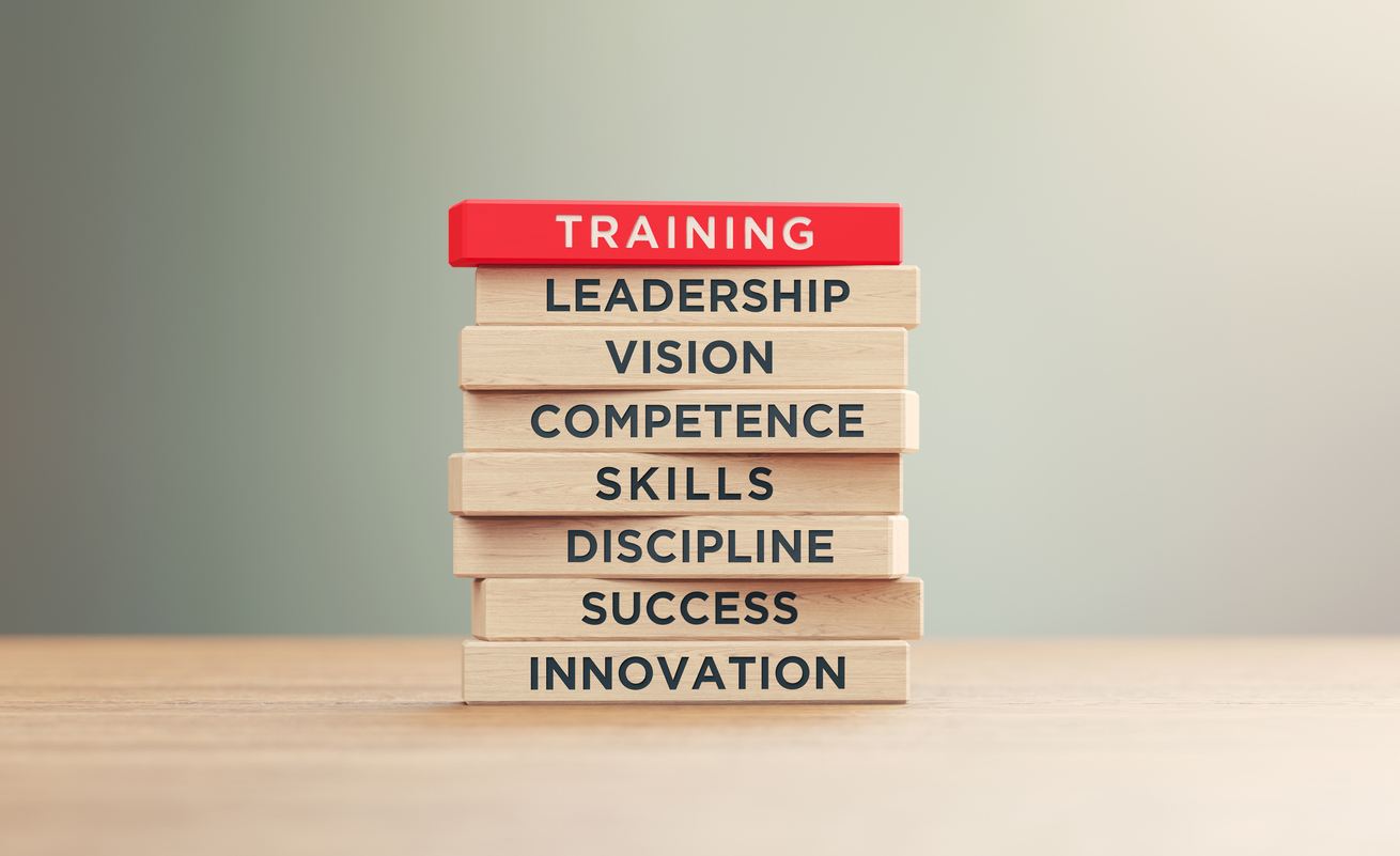 Training related words written woodblocks sitting on wood surface in front of a defocused background.