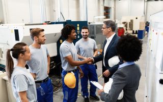 Corporate manager shaking hands with a worker while visiting a factory.