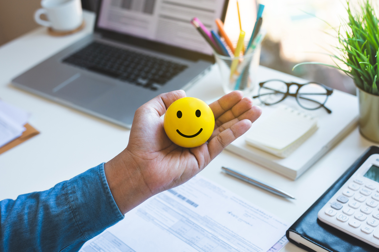 Emoticon ball on male hand on work table.happy life concepts.