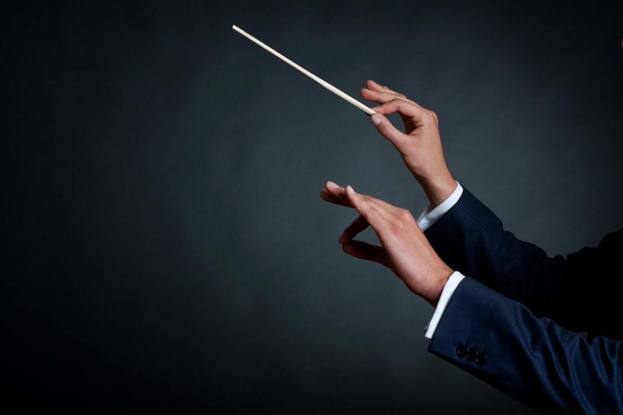 orchestra conductor directing with his baton in concert.