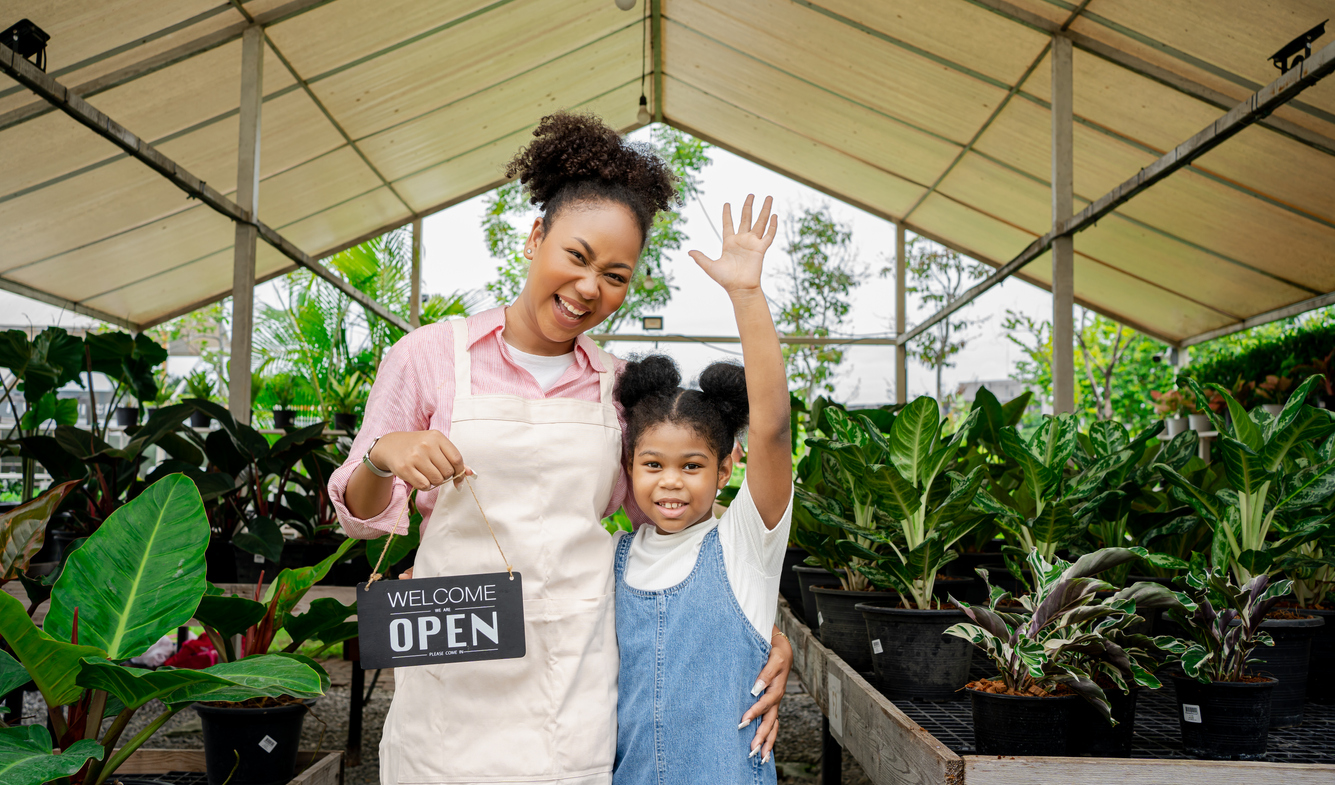 Mother and daughter with "we're open" sign