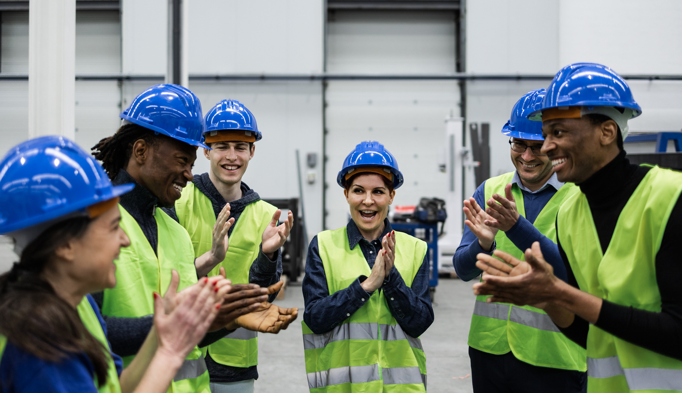Team of multiracial engineers clapping and smiling.