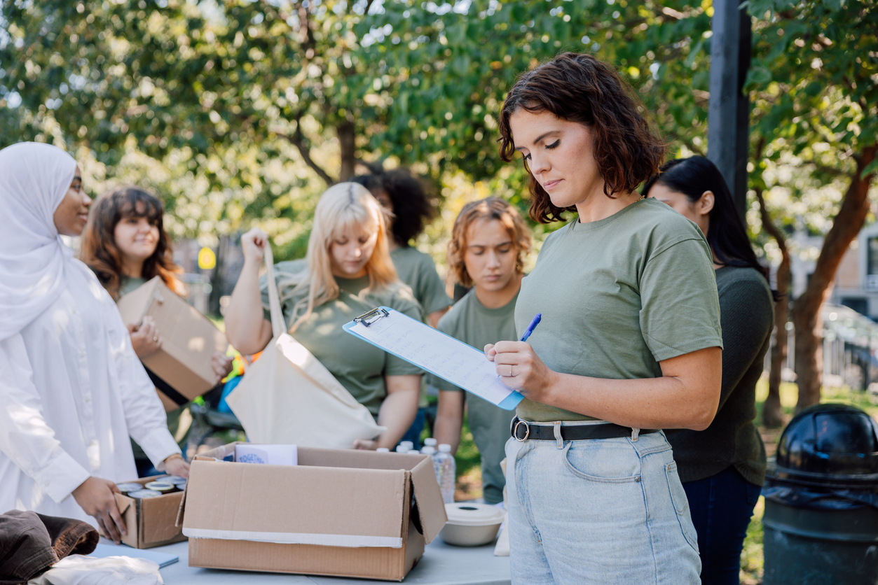 Non-Profit Leader - Woman with clipboard helping volunteers